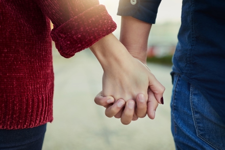Two people, a man and a woman, walking hand-in-hand