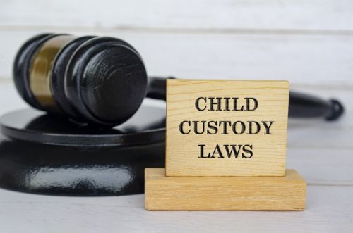 Child Custody Laws text engraved on wooden blocks with gavel background. Child custody concept.