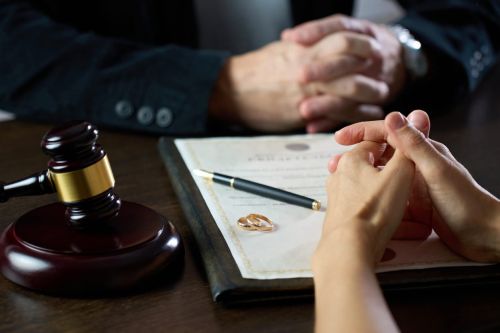 Couple sitting at table with divorce document, close-up, selective focus. Signing divorce agreement. Visual concept for a blog discussing uncontested vs contested divorce.