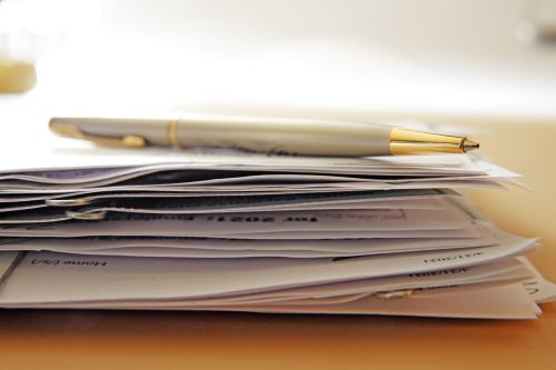 A ballpoint pen rests on top of a random stack of documents held together by paper clips. Photographed with a very shallow depth of field. Concept for Maryland Divorce Document Checklist