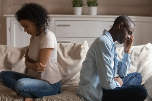 Unhappy couple sitting on couch. Wife and husband ignoring each other. They are having problems in their relationships and thinking on divorce mistakes.
