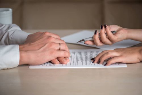 Hands of a woman and a man, signing divorce papers. Concept of What Happens if My Spouse Refuses to Sign Divorce Papers?