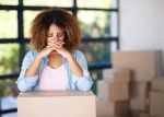 young woman looking upset packing boxes at home