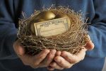 A senior male holds a nest that contains two golden eggs and a blank social security card. Concept for How Does Divorce Affect Social Security Benefits?